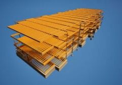 Gran estructura industrial de acero amarilla vista desde abajo contra un vasto cielo azul.